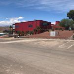 A large red building is sitting on top of a hill next to a parking lot.