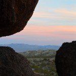 A couple of rocks sitting next to each other with a sunset in the background.