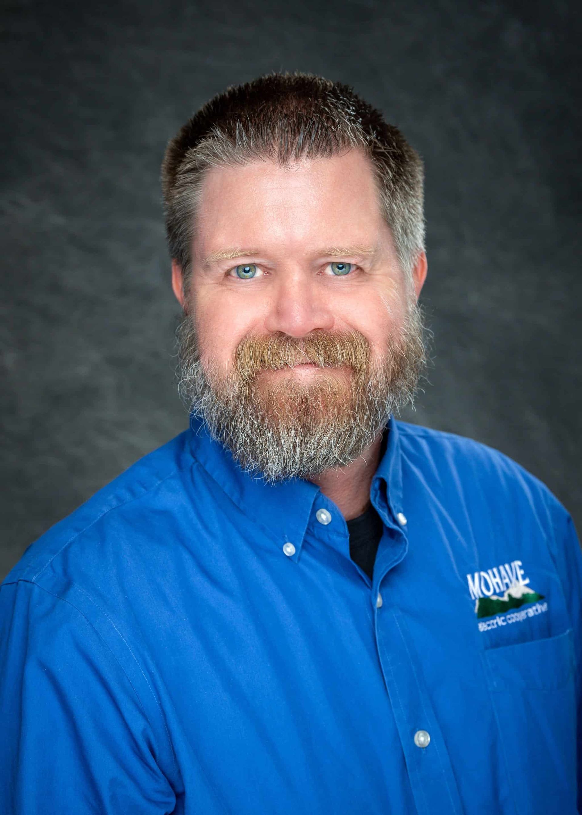 A man with a beard is wearing a blue shirt.