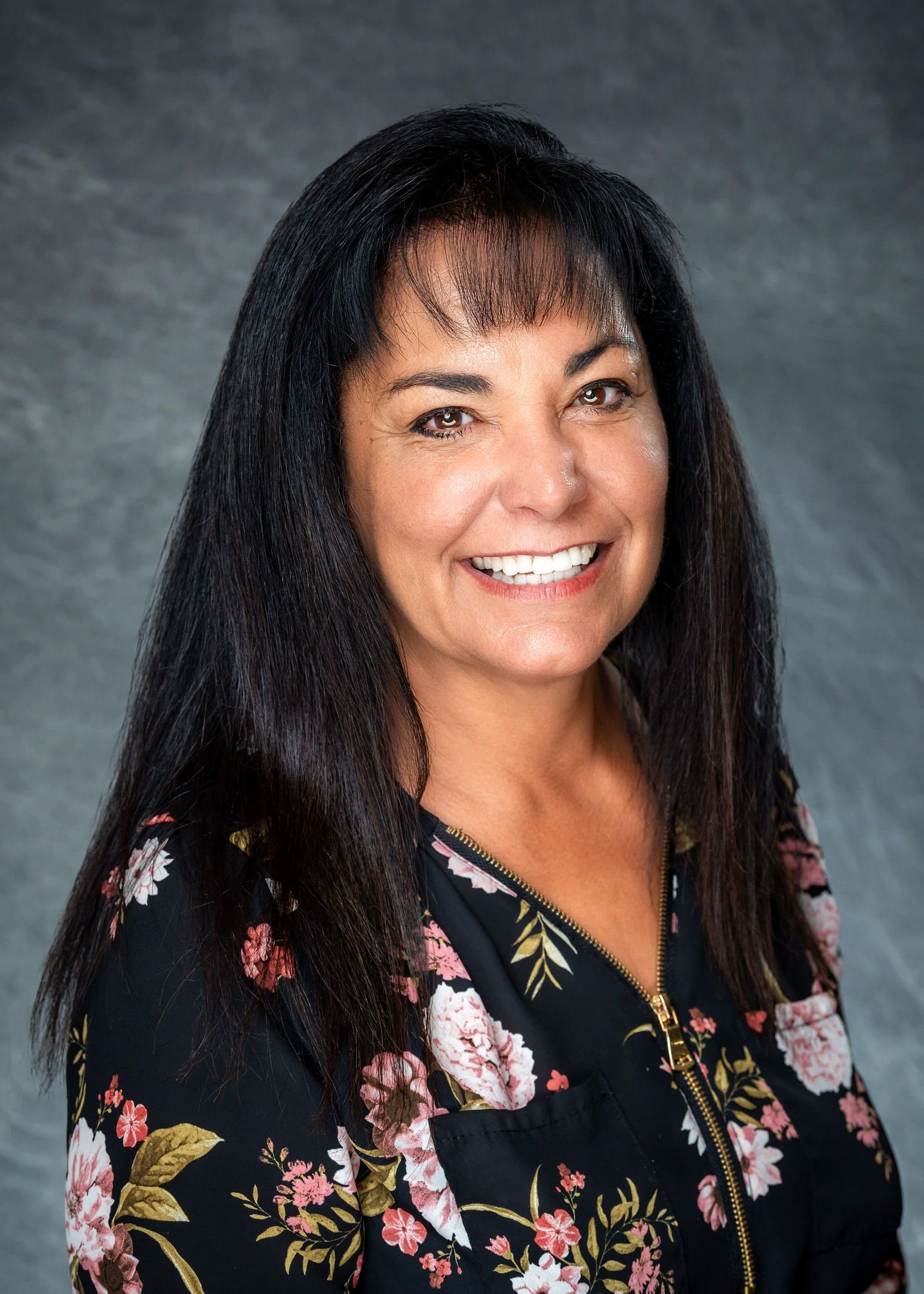 A woman in a floral shirt is smiling for the camera.