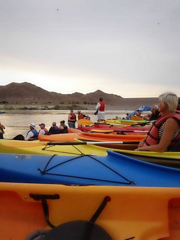 A group of people are sitting in kayaks on a lake