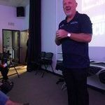 A man is standing in front of a projector screen in a room.