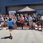 A woman is throwing a frisbee in front of a crowd of people.