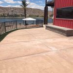 A patio with a view of a lake and a red building.