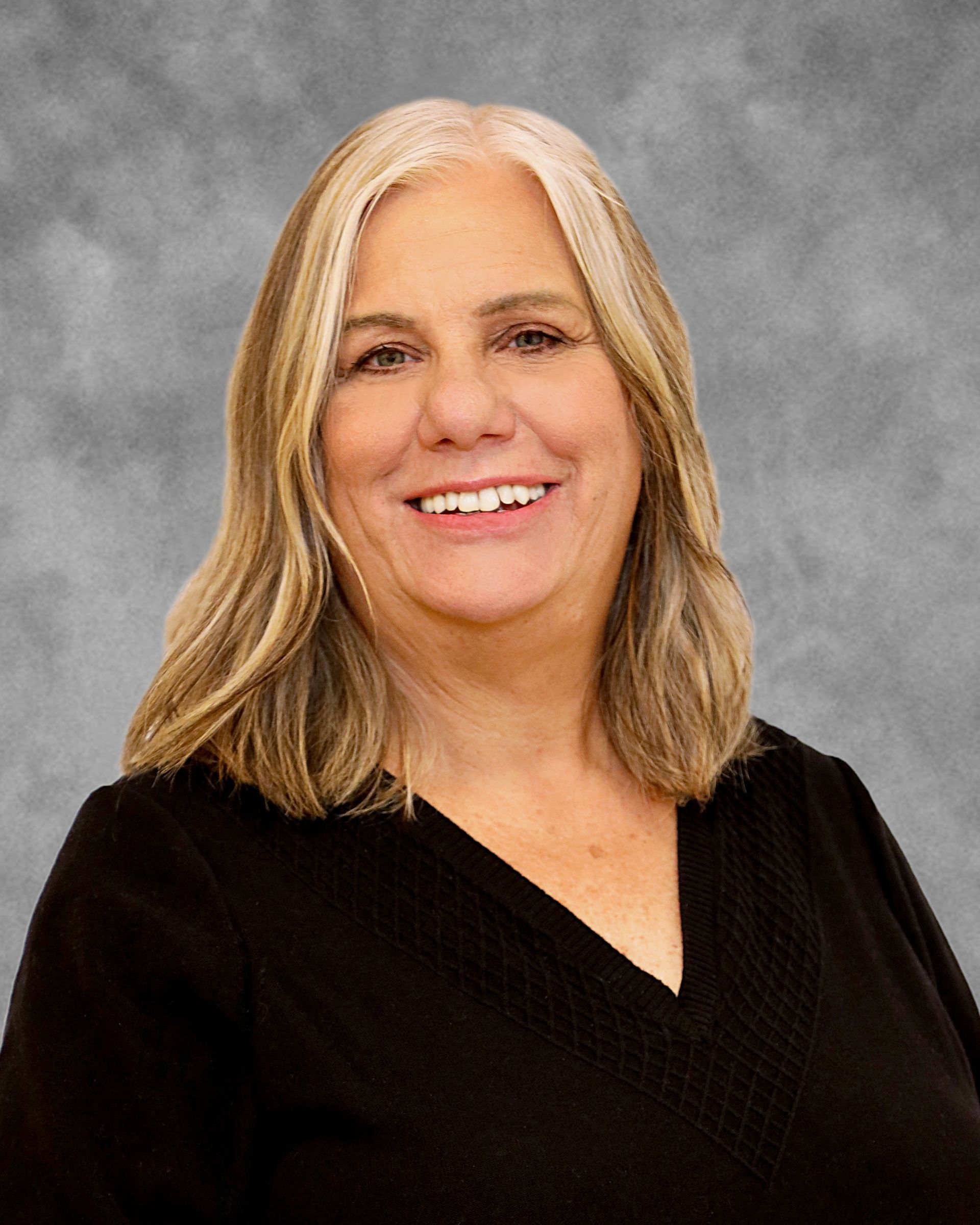 A woman in a black shirt is smiling for the camera.