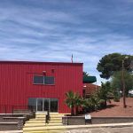 A red building with stairs leading up to it and a blue sky in the background.