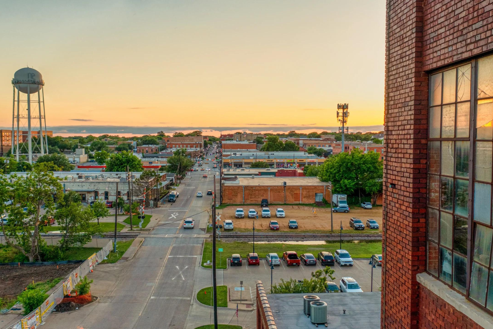 An aerial view of a city street at sunset with a water tower in the background.