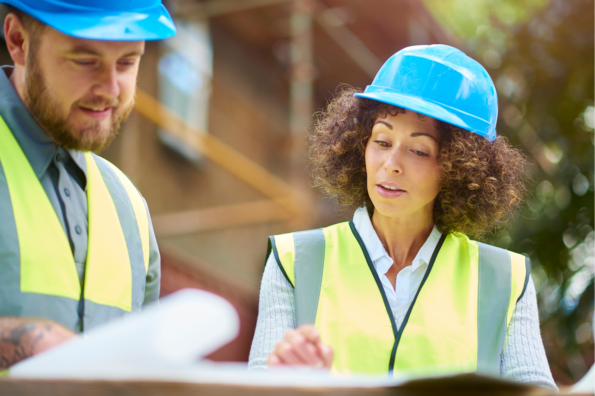 A construction worker is standing in front of a crane on a construction site.