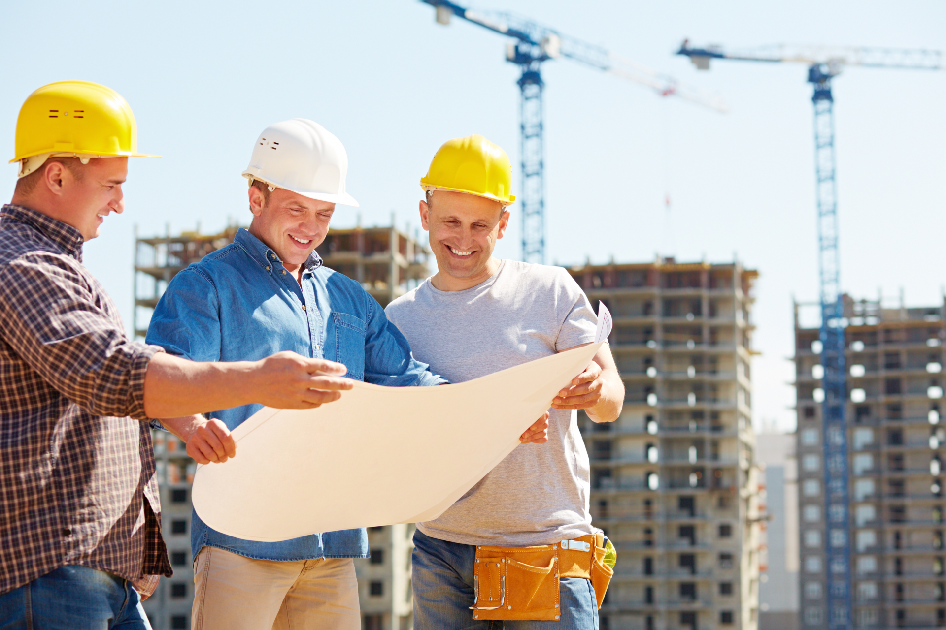 A construction worker is standing in front of a crane on a construction site.