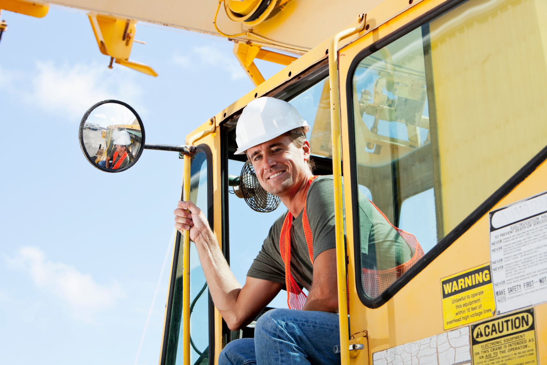 A construction worker is standing in front of a crane on a construction site.