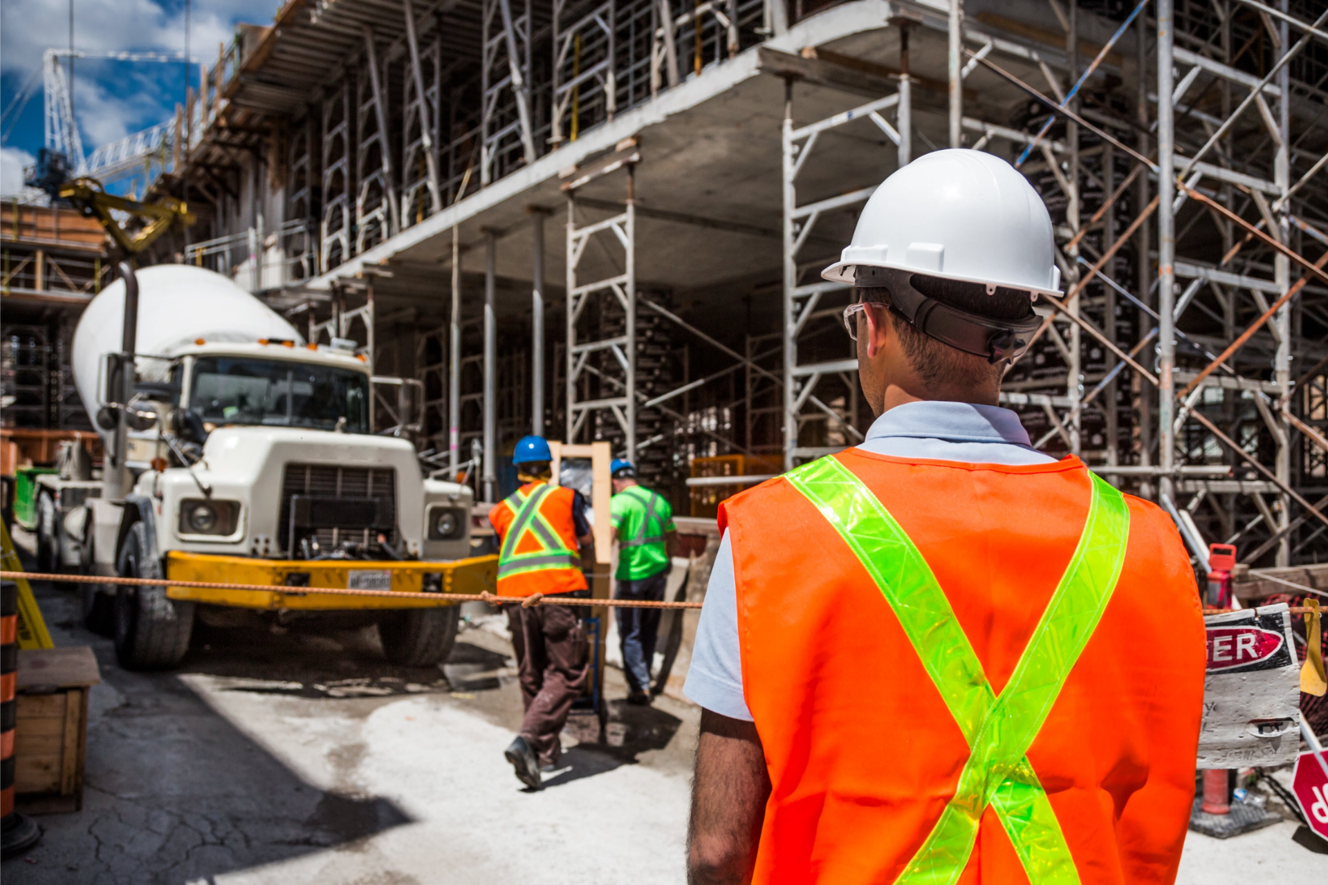 A construction worker is standing in front of a crane on a construction site.