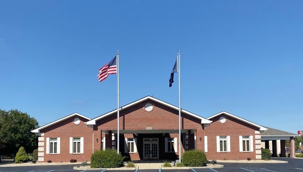 Brick building with US and POW-MIA flags under a clear blue sky.