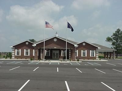 Brick building with flags and parking lot.