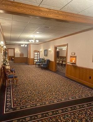 Long hallway with patterned carpet, wood trim, and seating.