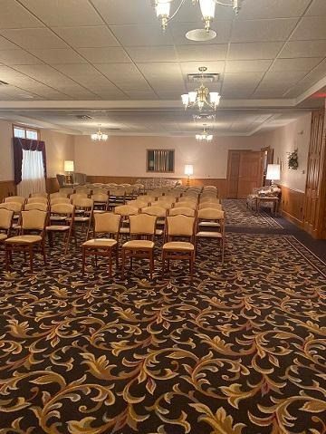 Empty room with rows of chairs, patterned carpet, and chandeliers.