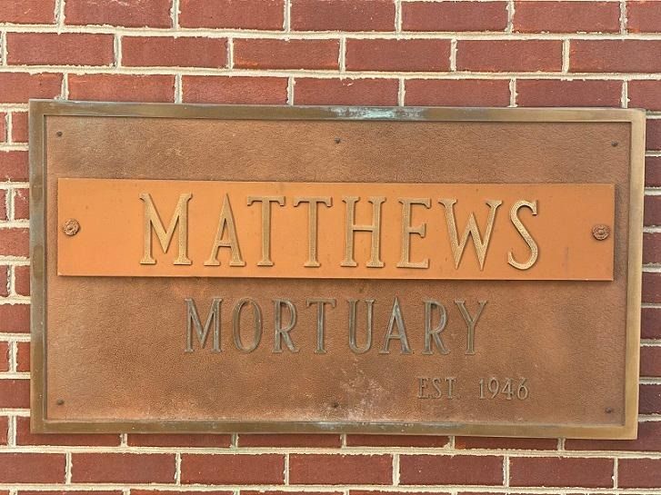 Bronze Matthews Mortuary sign on brick wall, established 1948.