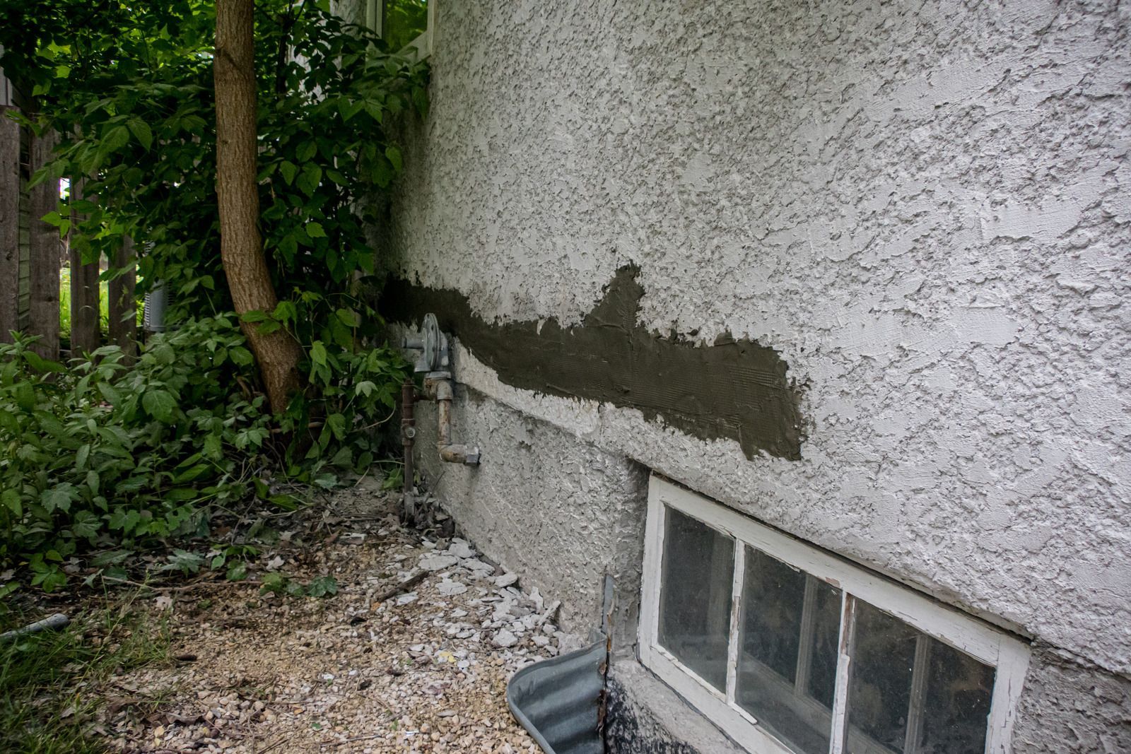 Person smoothing wet gray cement with a trowel, wearing orange gloves