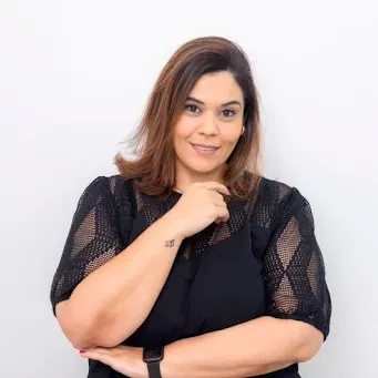 Uma mulher com um suéter amarelo está parada ao lado de uma taça de martini e um prato de camarão.