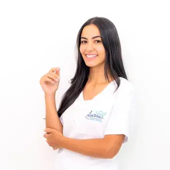 Uma mulher com longos cabelos pretos está vestindo uma camisa branca e sorrindo.