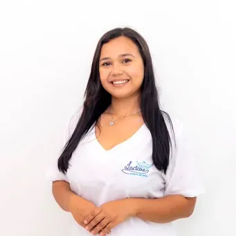 A mulher está vestindo uma camisa branca e sorrindo para a câmera.