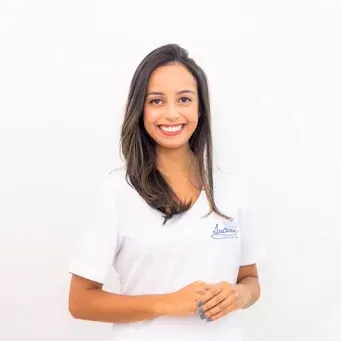 Uma mulher de camisa branca sorri para a câmera.