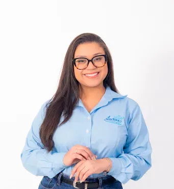 Uma mulher usando óculos e uma camisa azul está sorrindo.