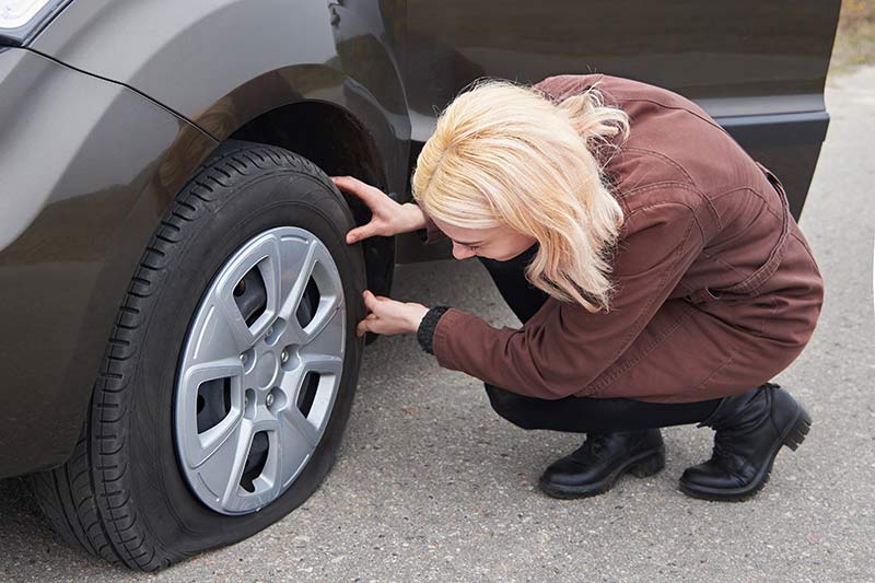 Woman Checking Her Car Tire