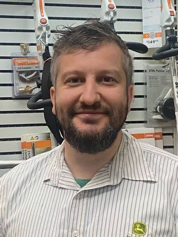 A man with a beard is wearing a striped shirt and smiling.