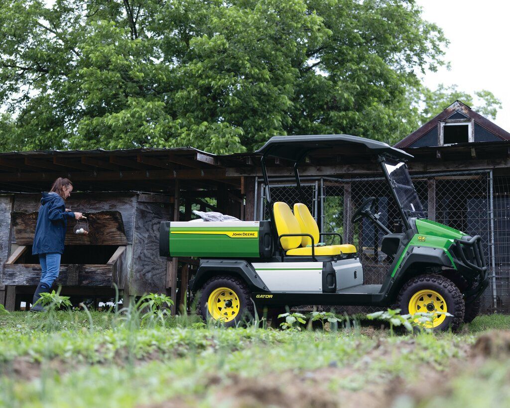 A green and black utility vehicle is parked in a dirt field.