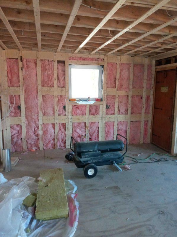 A room with pink insulation and a heater in it.