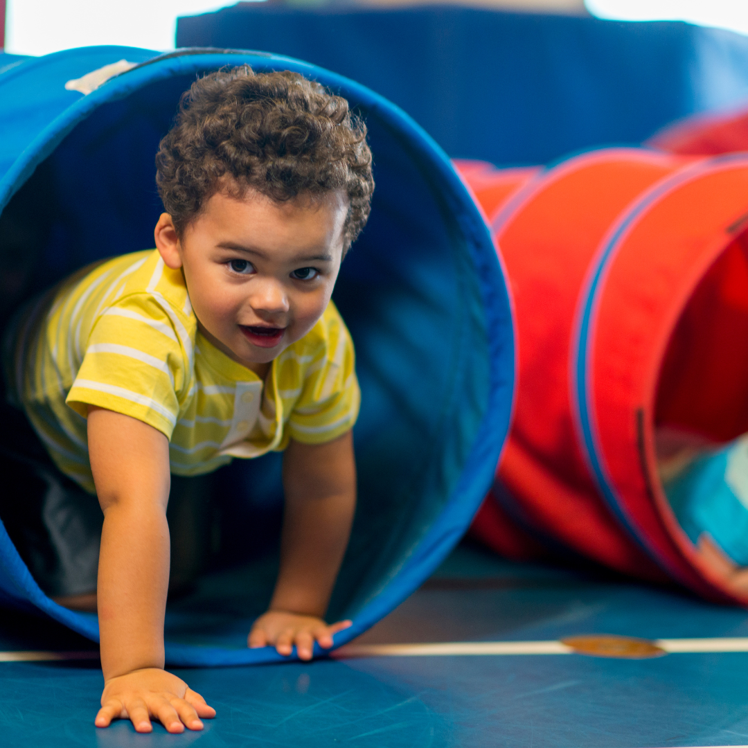 A young boy is crawling through a blue tunnel