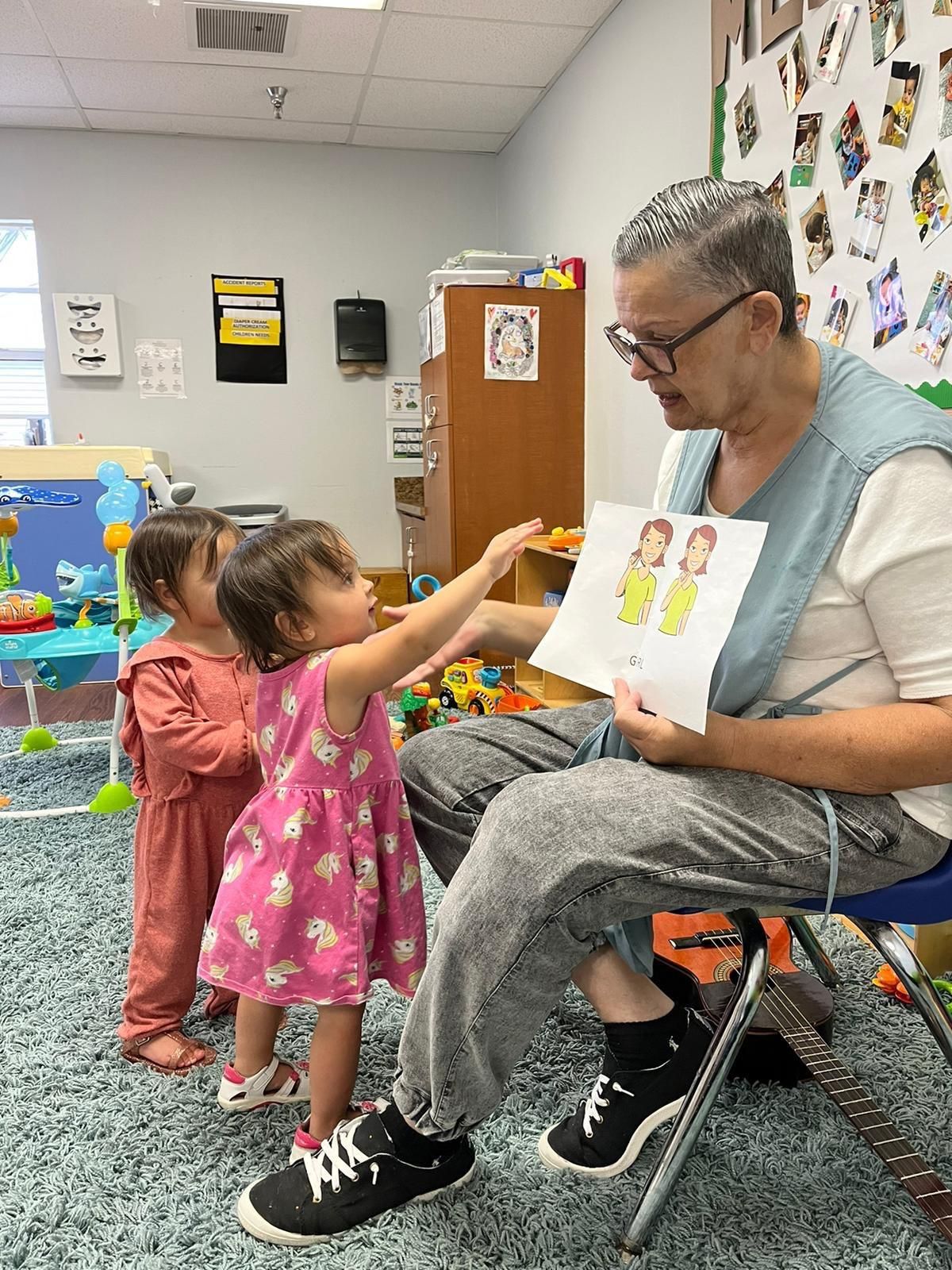 A woman is sitting in a chair reading a book to two little girls.