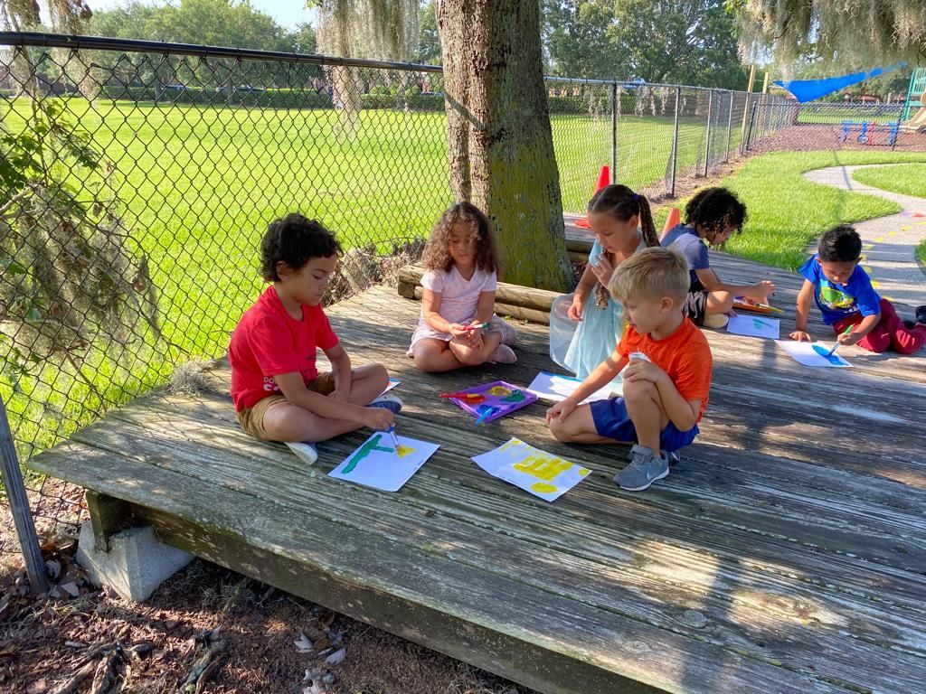 A group of children are sitting on a wooden bench in a park.