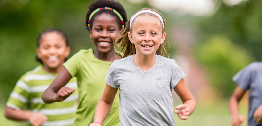 A group of young girls are running in a park.