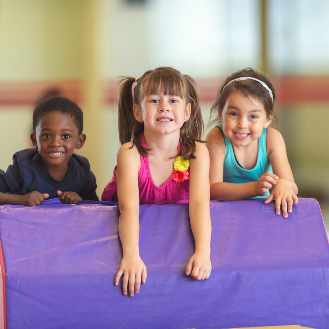 A boy and two girls are playing on a purple mat