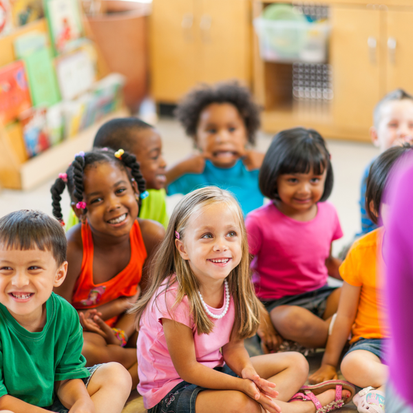 A group of children are sitting on the floor in a classroom.