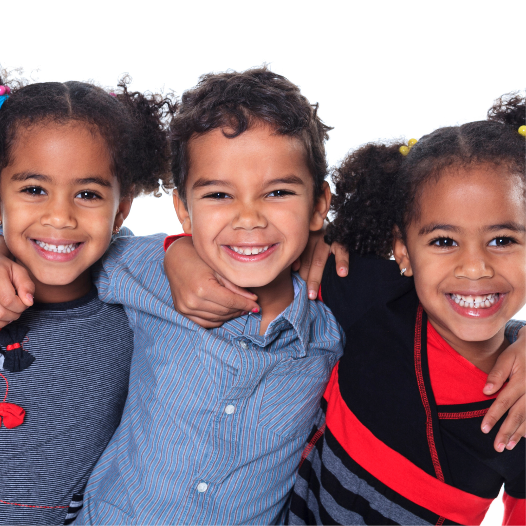 Three children are posing for a picture and smiling for the camera