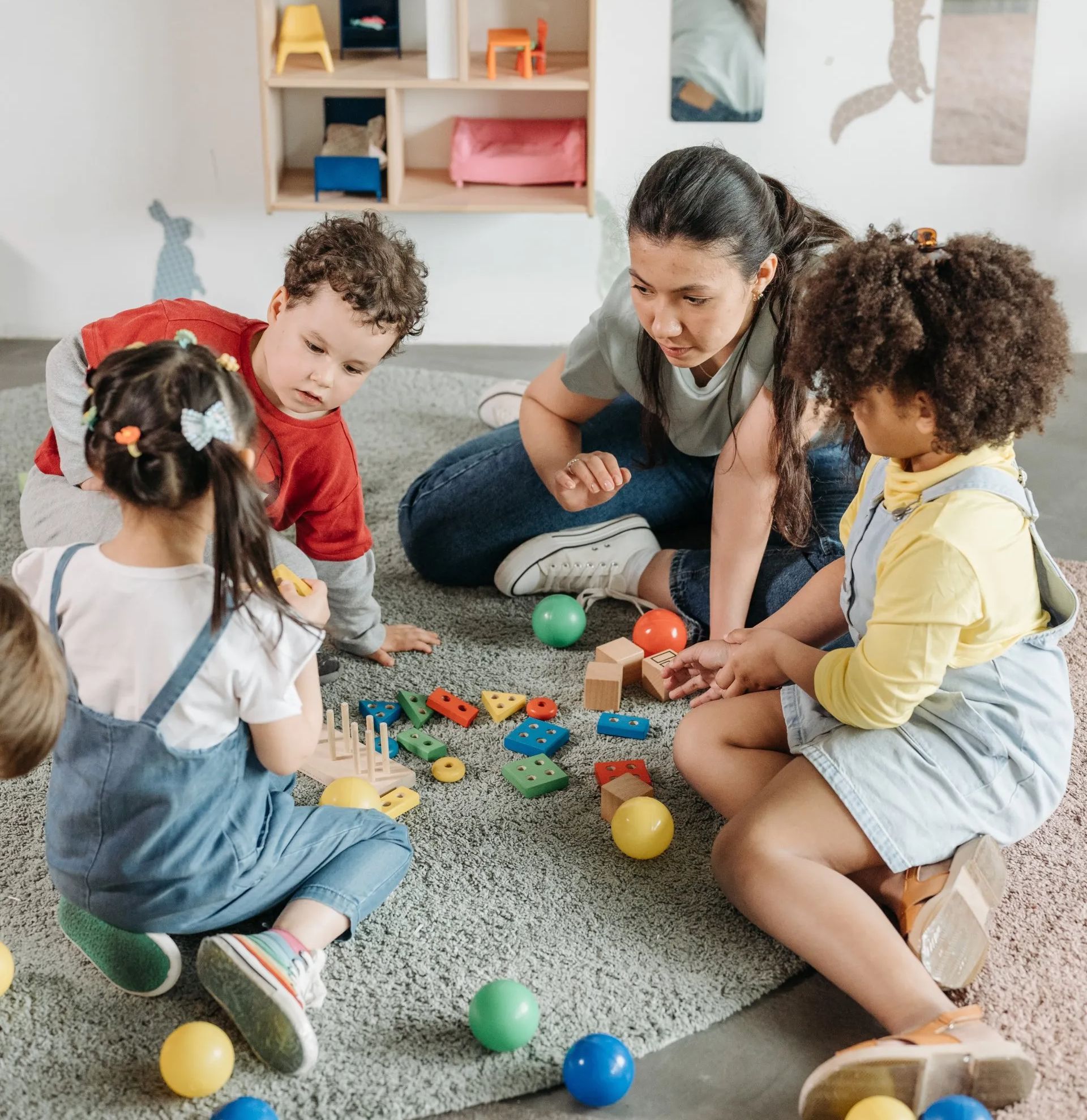 A group of children are sitting on the floor playing with toys.