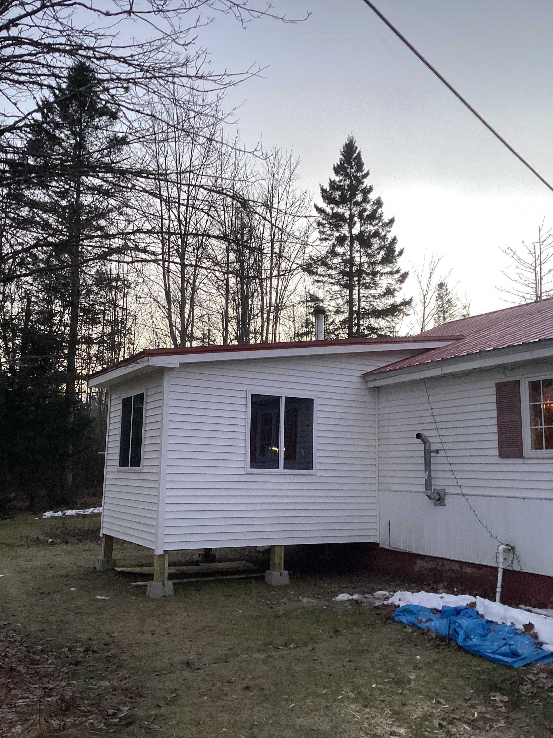 A white house with a red roof is surrounded by trees
