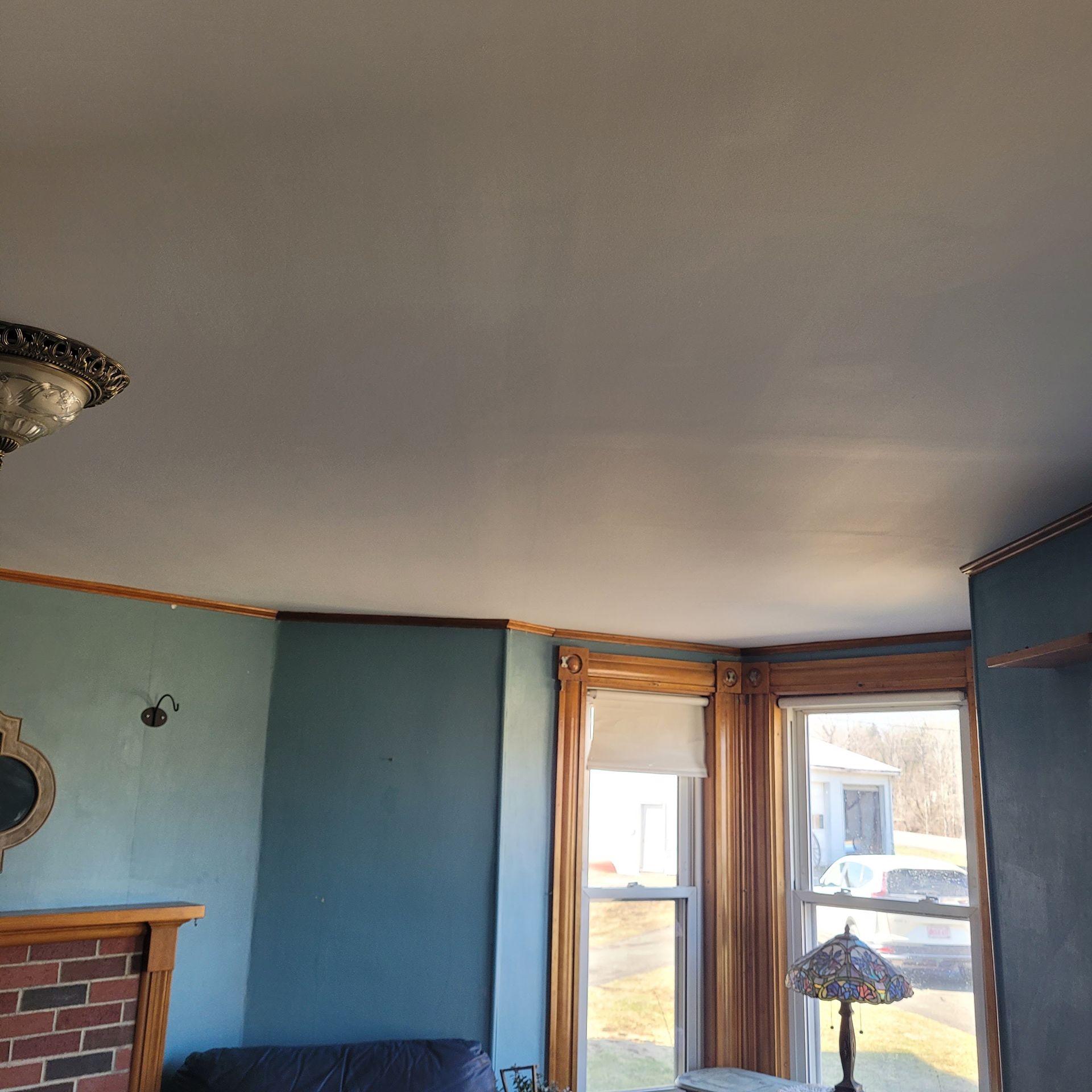 A living room with a couch , fireplace , lamp and windows.