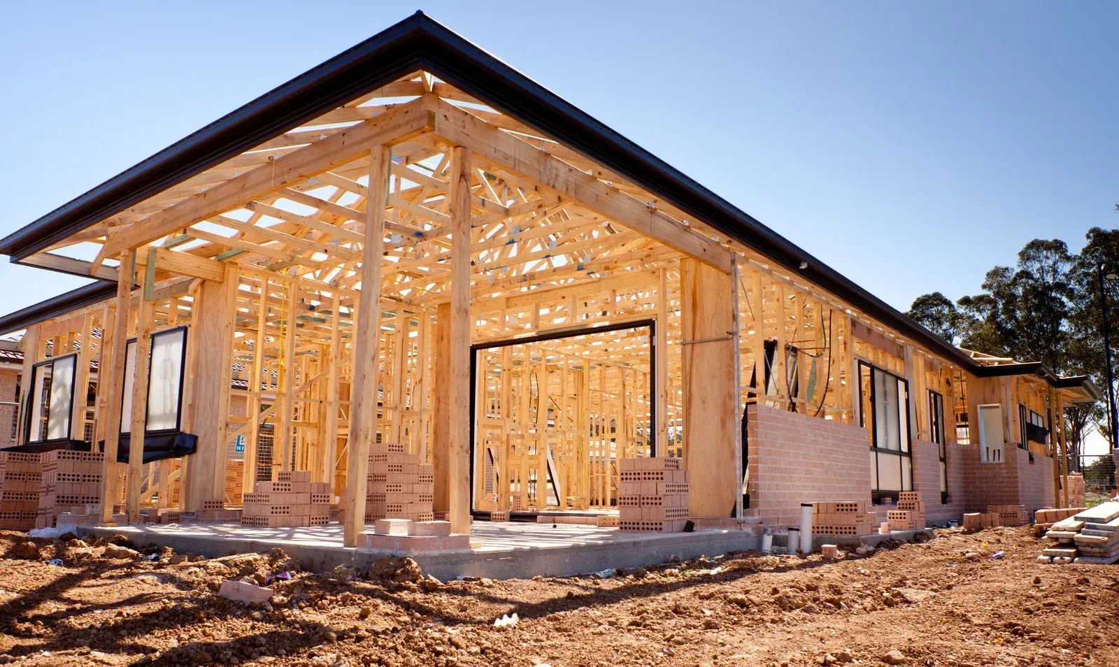 A large wooden house is being built in the dirt.