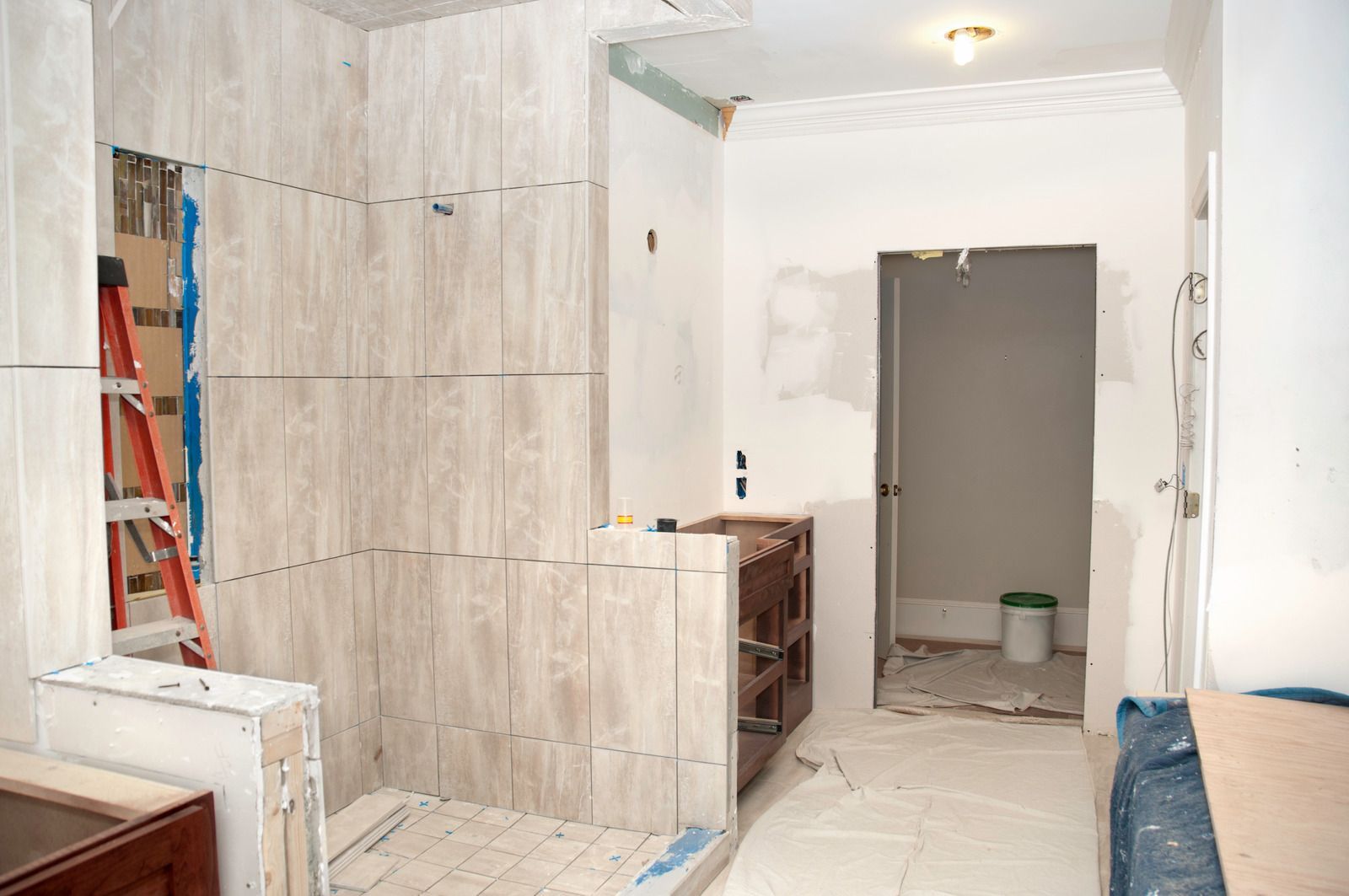 A bathroom is being remodeled with tile and a ladder.