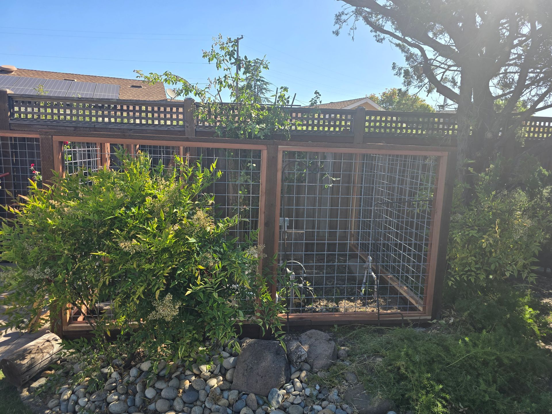 A wooden fence is surrounded by bushes and rocks.