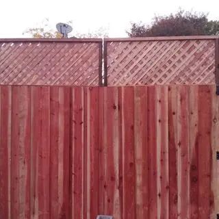 A red wooden fence with a lattice on top of it.