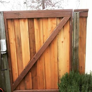 A wooden gate with a z on it is sitting next to a bush.