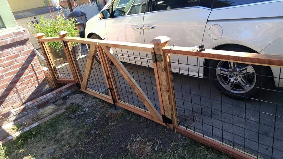 A white car is parked behind a wooden fence.