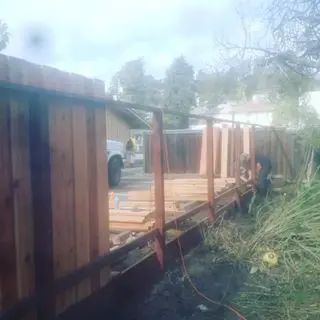 A wooden fence is being built in the backyard of a house.