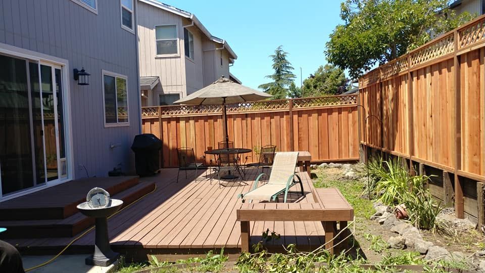 A backyard with a wooden deck and a wooden fence