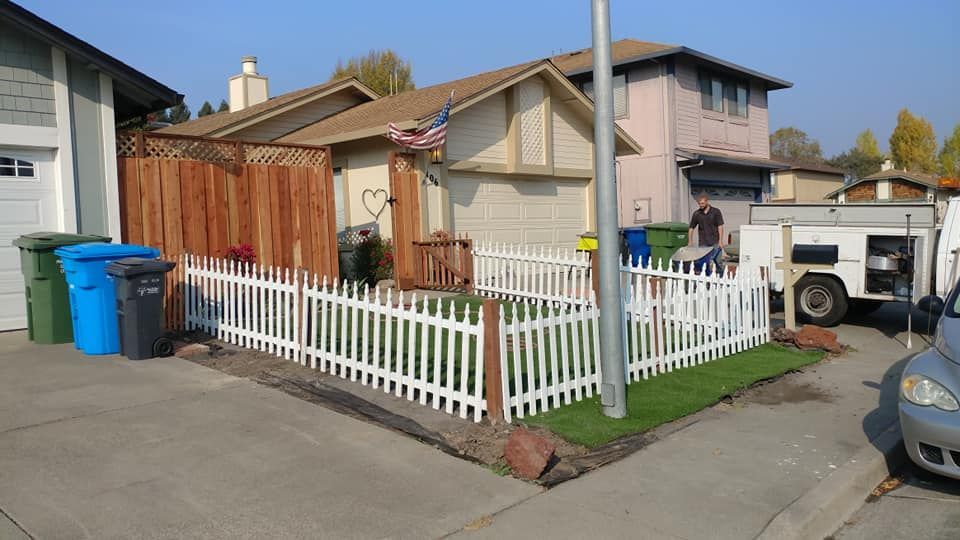 A white picket fence is in front of a house.