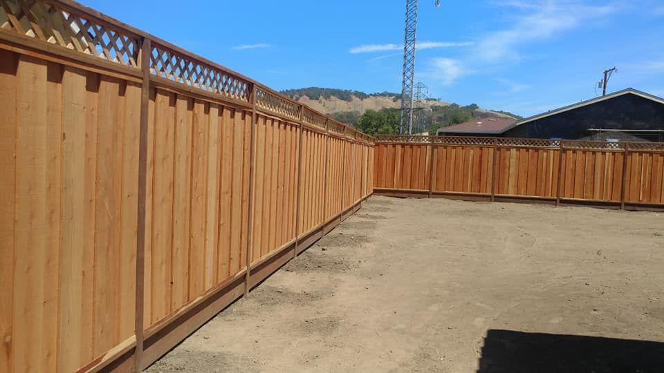 A wooden fence is sitting in the middle of a dirt field.